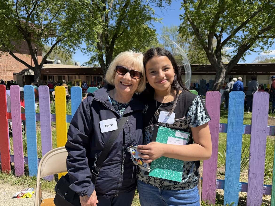 older woman and school age in front of fence at school