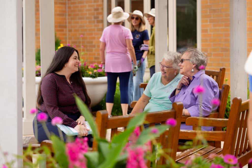 young woman sitting with older adult women outdoors